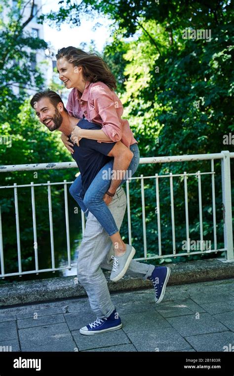 Happy man running and carrying woman piggyback Stock Photo - Alamy