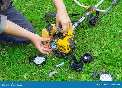 Worker Repairs a Starter in a Trimmer or Lawn Mower that Lies on the Grass Stock Image - Image ...