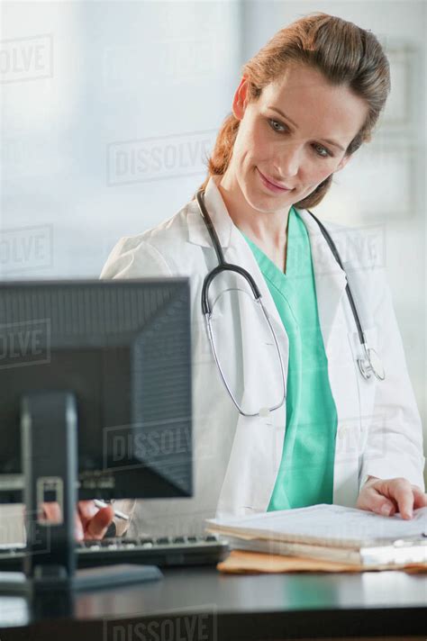 Female doctor looking at computer monitor - Stock Photo - Dissolve