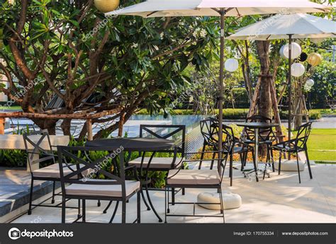 Cafe tables and chairs outside with big white umbrella and plant — Stock Photo © tisomboon ...