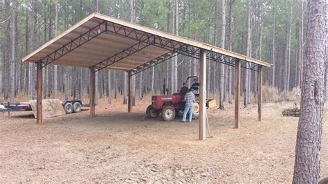 a man on a red tractor pulling a trailer in the middle of a pine forest