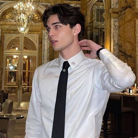 a man wearing a white shirt and black tie in a room with chandeliers