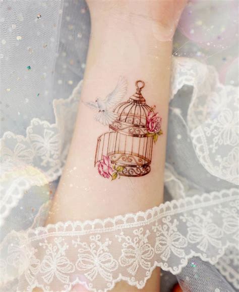 Dove and bird cage tattoo located on the wrist.