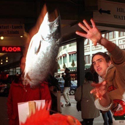 a man reaching out to catch a fish in the air while another person looks on