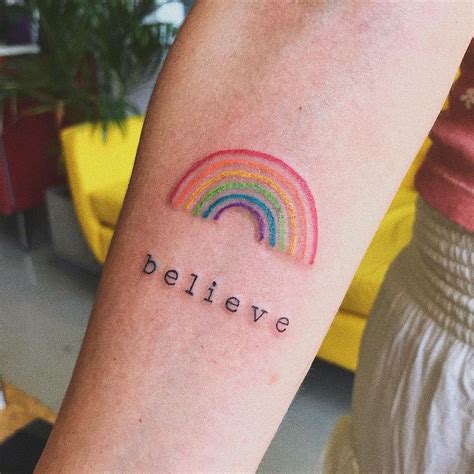 a person with a rainbow tattoo on their arm that says believe and the words below it are written ...