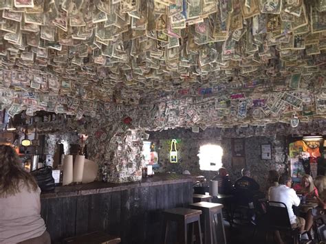 people sitting at tables in a restaurant covered with money bills hanging from the ceiling above ...