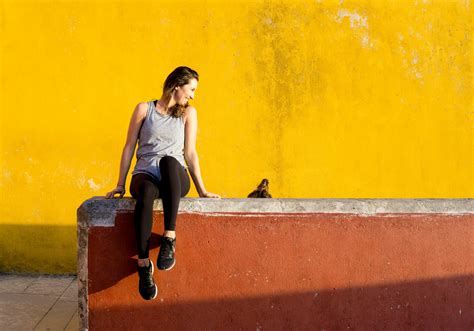 Smiling Woman Sitting on Orange Barrier · Free Stock Photo