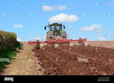 man using tractor and ridging machine to prepare furrows for ...