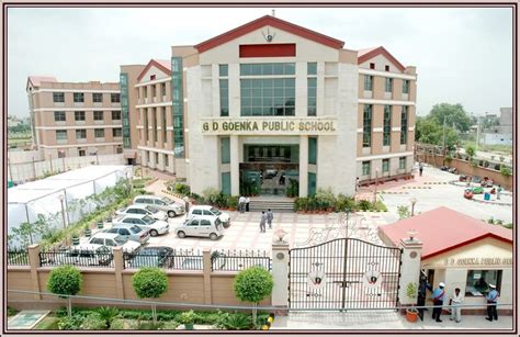 an aerial view of a school building with cars parked in the driveway and people walking around