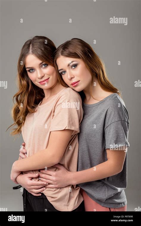 portrait of beautiful twin sisters hugging each other and looking at ...