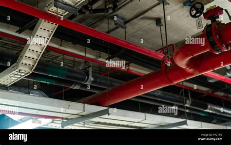 Fire sprinkler system with red pipes hanging from ceiling inside building. Fire Suppression ...