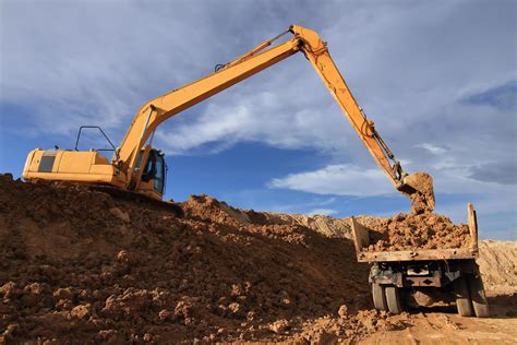 Heavy excavator loading dumper truck with sand in quarry over blue sky 10326515 Stock Photo at ...