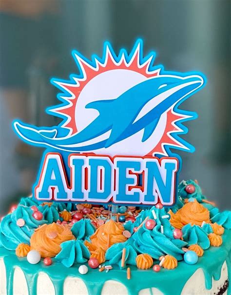 a birthday cake decorated with dolphins and the word aden on it's top