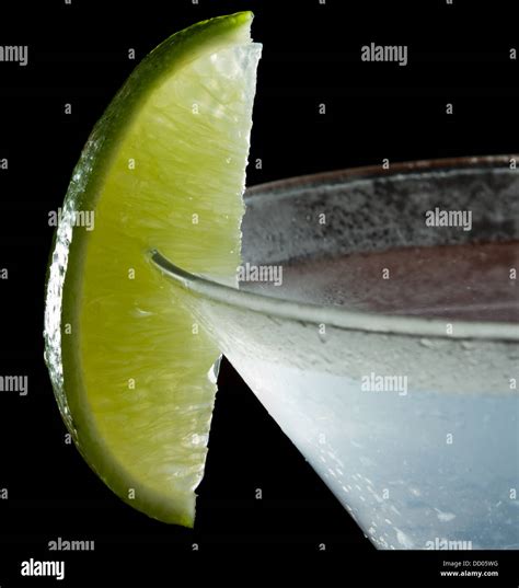 lime wedge on the rim of a martini glass used as a garnish isolated on a black background Stock ...