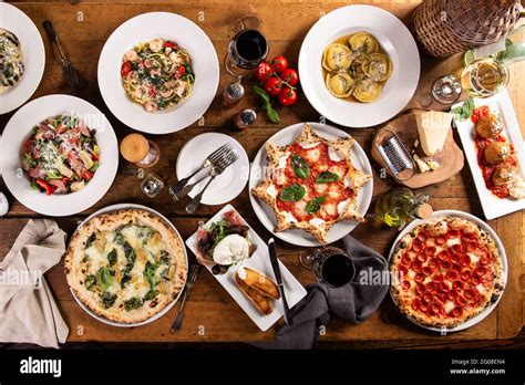 Big dinner table with italian food, pizzas and pastas Stock Photo - Alamy