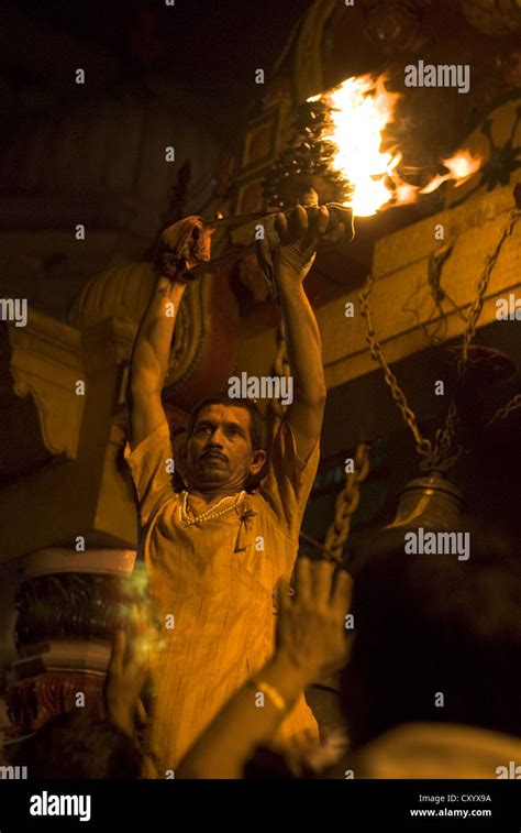 A Hindu Pujari (priest) raises flaming offerings from worshippers at Vishram ghat, Mathura ...