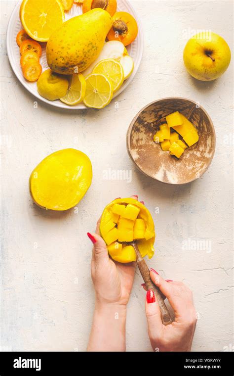 Mango preparation step by step. Female hands girl take mango cubes from the peel with a spoon on ...