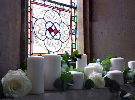 candles and flowers sit in front of a stained glass window