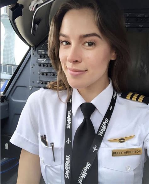 a woman wearing a pilot's uniform is smiling at the camera while sitting in an airplane