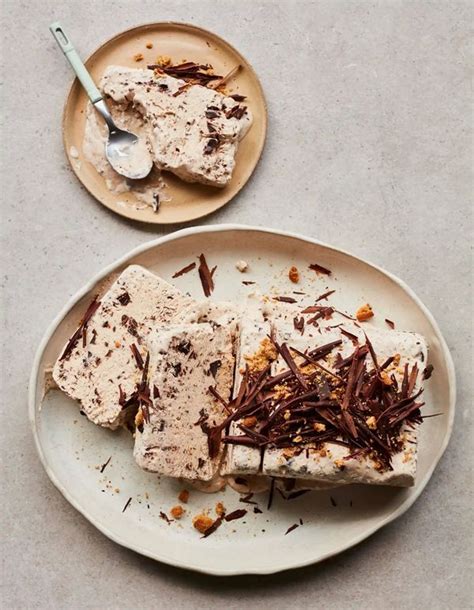 An oval beige plate with a block of semifreddo that is partially sliced ...