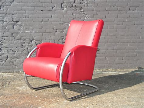 a red leather chair sitting in front of a brick wall with a metal frame around it