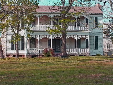 an old white house sitting on top of a lush green field