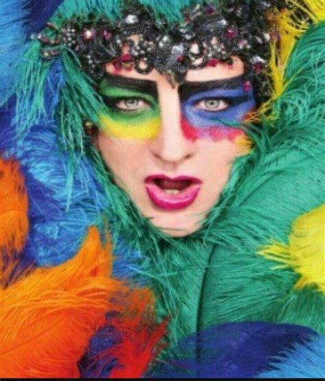 a woman with colorful makeup and feathers on her face