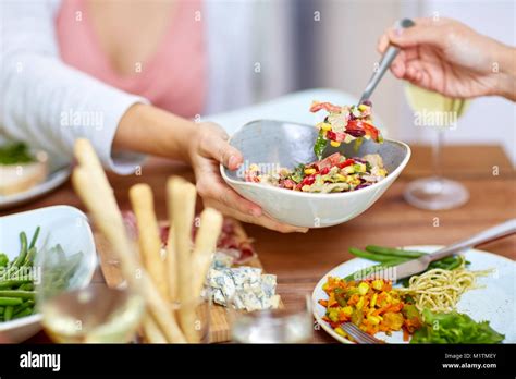 people eating salad at table with food Stock Photo - Alamy