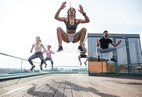 Group of young people doing exercise outdoors on terrace, sport and healthy lifestyle concept. A ...