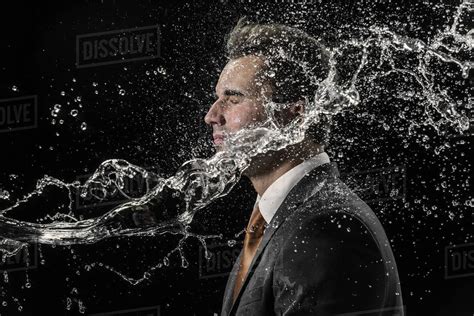 Water splashing on businessman against black background - Stock Photo ...