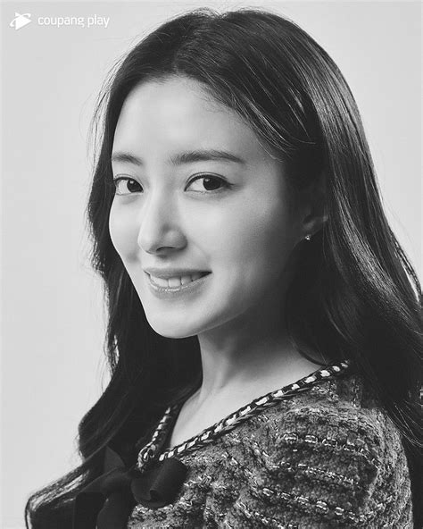 black and white photograph of a woman with long dark hair wearing a sweater smiling at the camera