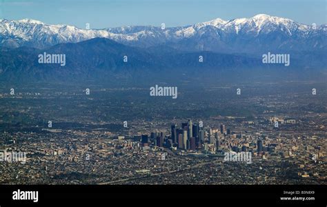 aerial view above Downtown Los Angeles with snow covered San Gabriel ...