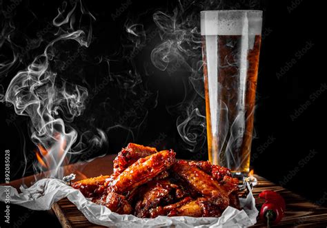 glass of fresh beer and fried chicken wings on wooden table on black background Stock Photo ...