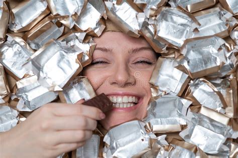 The Face of a Caucasian Woman Surrounded by Candy Wrappers. the Girl Eats a Bar of Chocolate ...