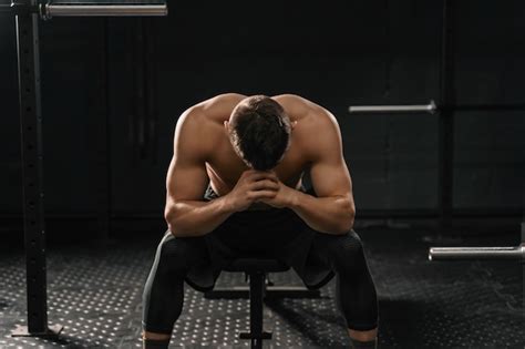 Premium Photo | Strong sporty man sitting on gym bench suffering ...