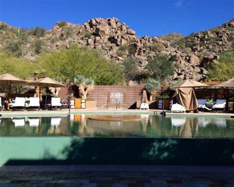 an outdoor swimming pool with lounge chairs and umbrellas next to the mountain side area