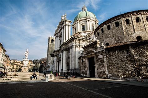 an old building with two towers and people walking around it