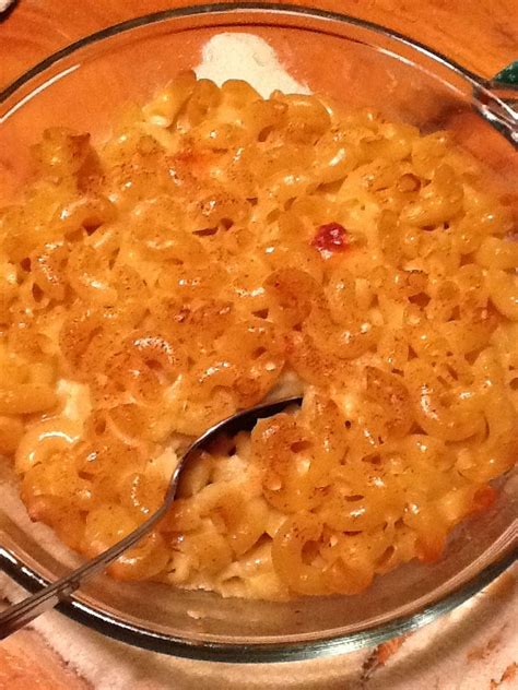 a glass bowl filled with macaroni and cheese on top of a wooden table