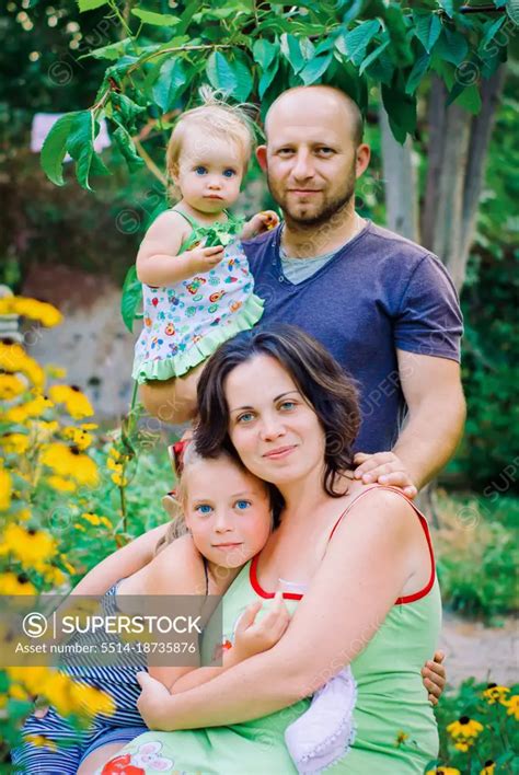 Portrait Of Happy Family In Garden At Home - SuperStock