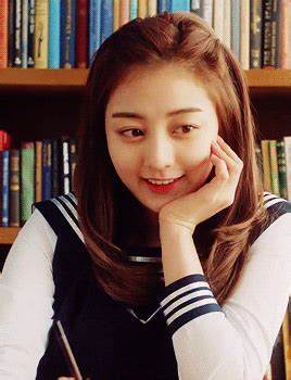 a woman sitting at a desk in front of a bookshelf holding a pen and paper