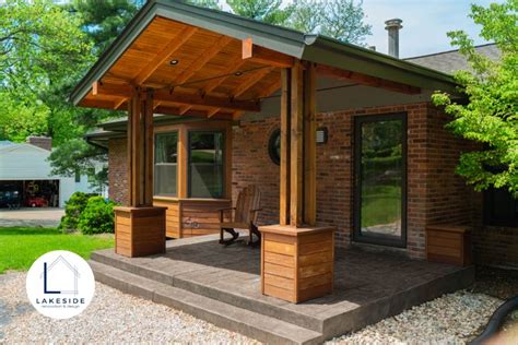 a covered patio with two wooden chairs on the front porch and an attached pergolan roof