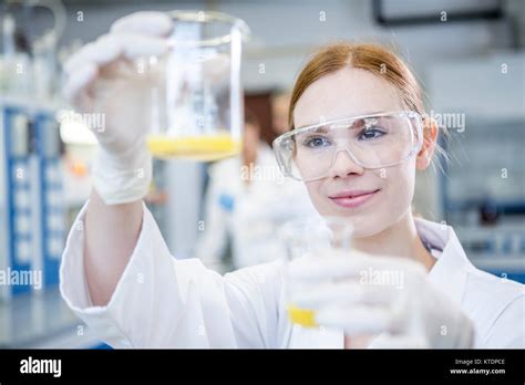 Scientist in lab holding up two beakers with liquid Stock Photo - Alamy