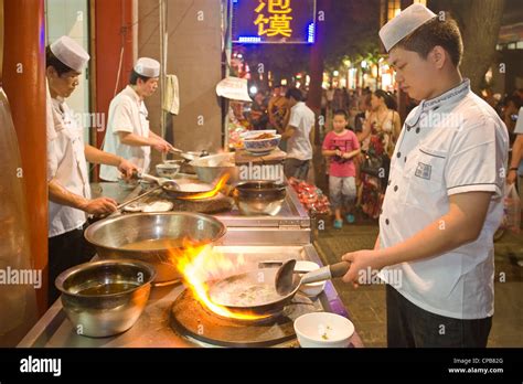 Chinese chefs cooking over a traditional gas burning stove and wok at a restaurant in Moslem ...