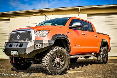 an orange truck is parked in front of a garage with its wheels on the ground