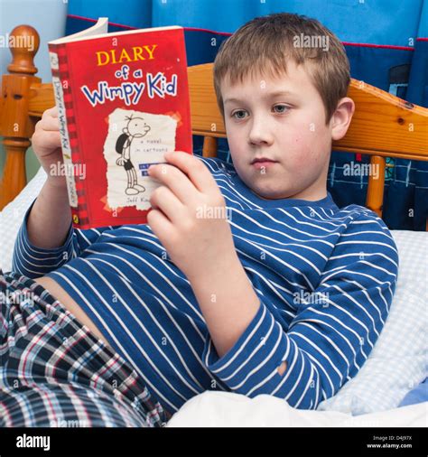 A nine year old boy reading the Diary of a wimpy kid childrens book ...