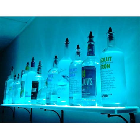 bottles are lined up on a shelf in front of a blue light that is reflecting off the wall