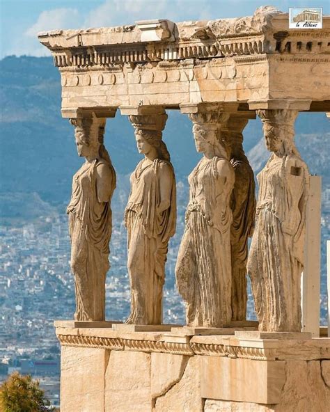 some statues on the side of a building with a city in the backgroud