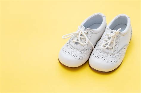 Premium Photo | White baby shoes on yellow