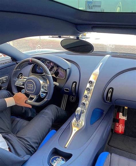 a man sitting in the driver's seat of a blue sports car with his hands ...