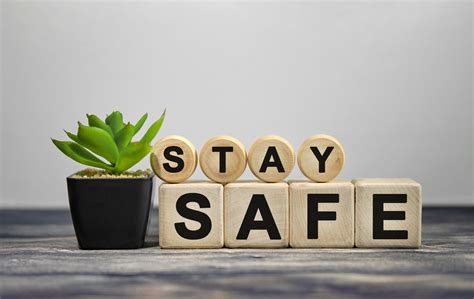 STAY SAFE - text on wooden cubes, green plant in black pot on a wooden background - The O ...